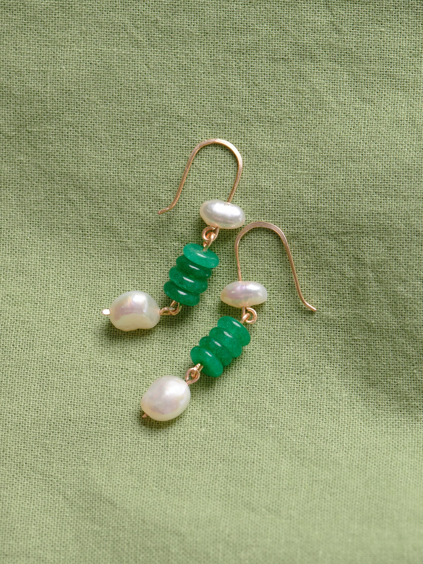 Closeup product photo of handmade Fortuna Earrings by Studio Greco. These dangle earrings feature green onyx and freshwater pearls suspended on tarnish-resistant gold-colored wire.