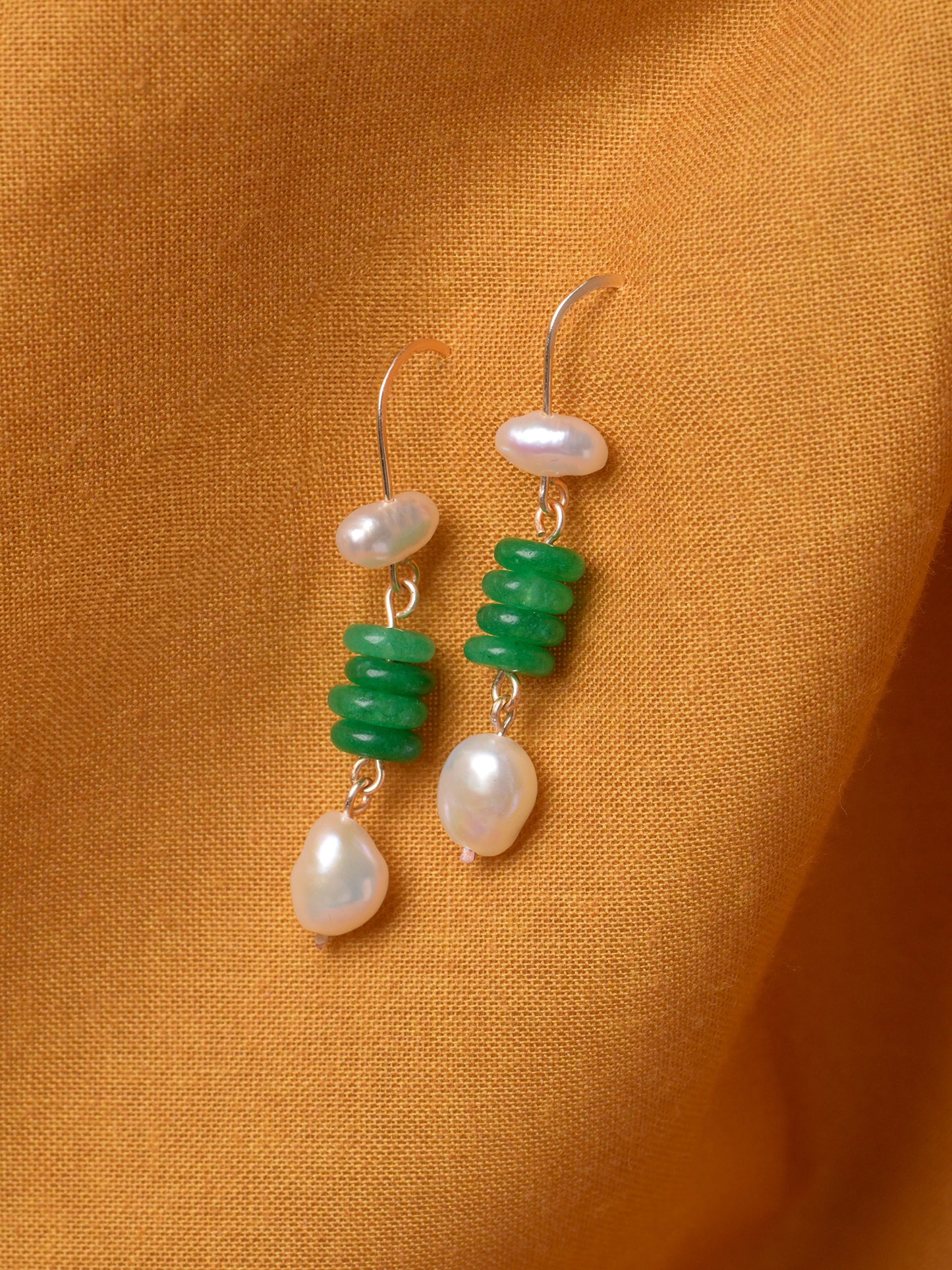 Closeup product photo of handmade Fortuna Earrings by Studio Greco. These dangle earrings feature green onyx and freshwater pearls suspended on tarnish-resistant gold-colored wire.